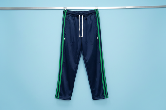 Navy blue tracksuit pants with green stripes on a white surface