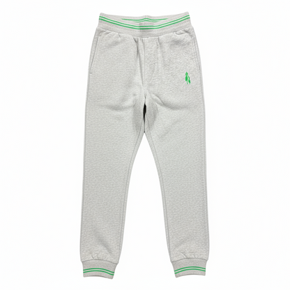 Grey sports trousers with green stripes and a logo on the left leg, displayed in a packed state with a visible green and white striped fabric on top.