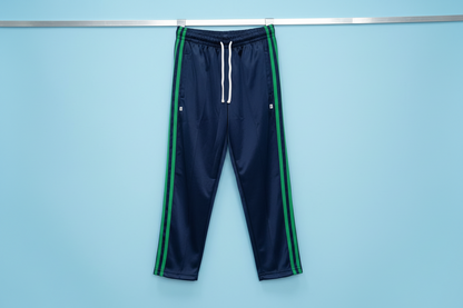 Navy blue tracksuit pants with green stripes on a white surface